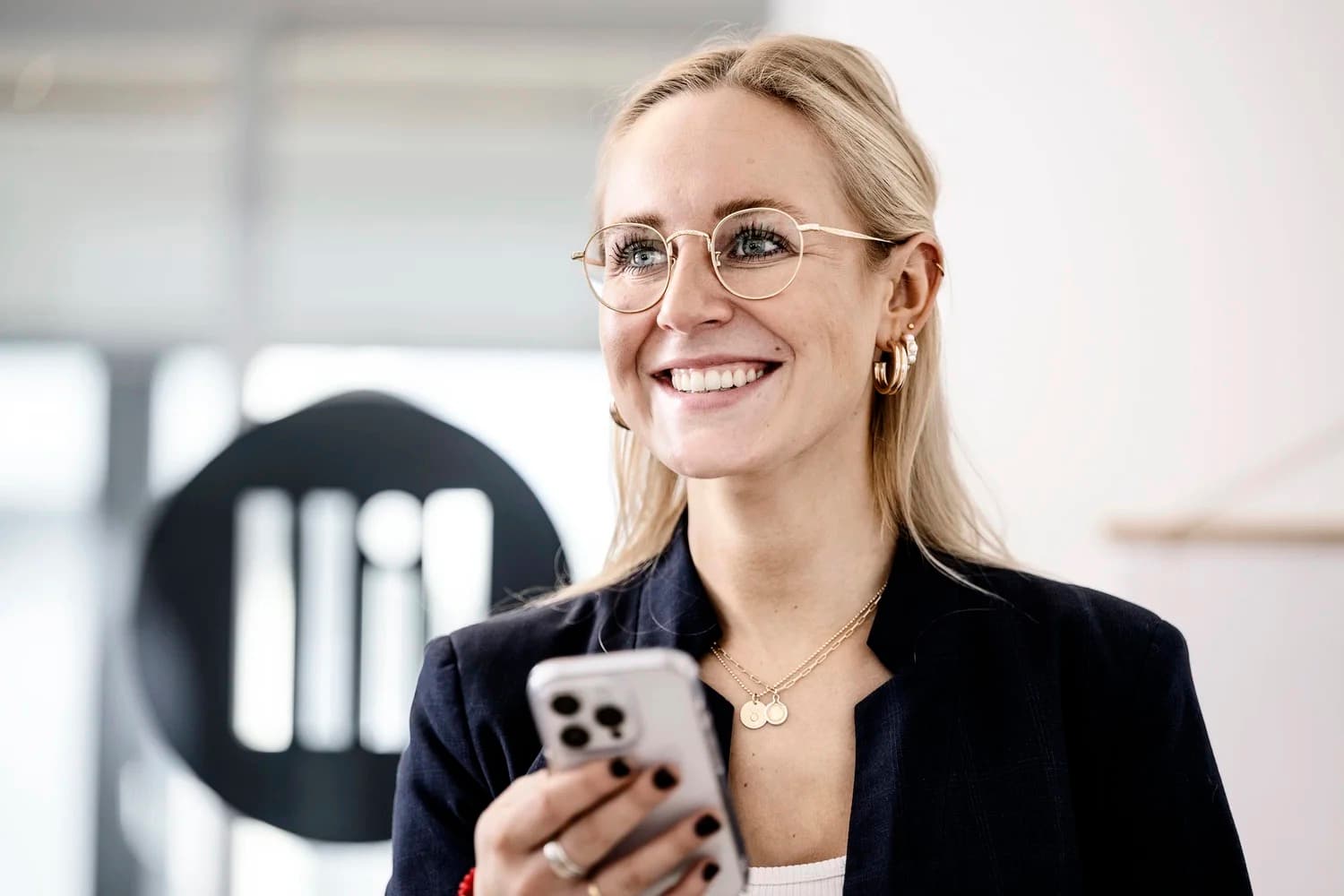 Team-Mitarbeiterin von LILL Social Media Kontor im Hamburger Büro vor dem LILL-Logo an der Wand