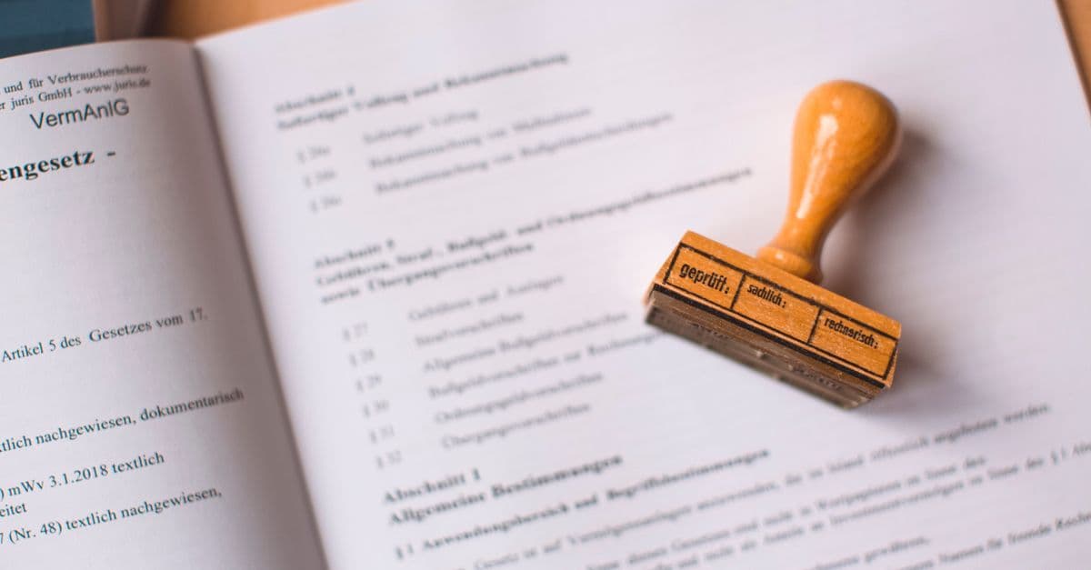 Nahaufnahme eines Rechtsdokuments mit aufgesetztem Holzstempel zur Beglaubigung