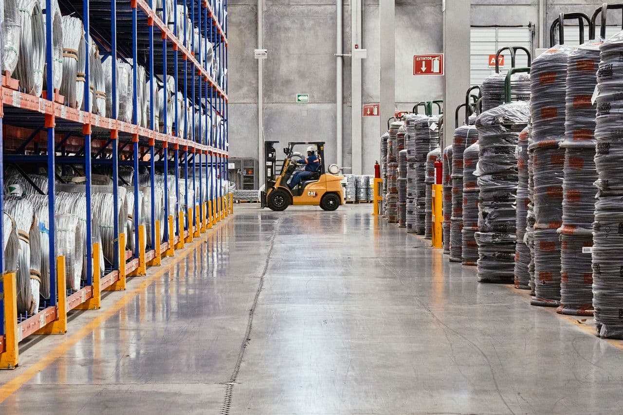 Ein Gabelstapler ist in einem Industrie-Lager mit gestapelten Gütern im Einsatz. Eine effiziente Lagerumgebung.