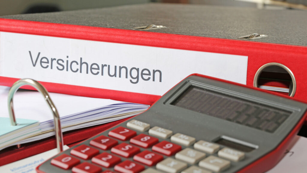Nachforderung von der Rentenversicherung an Selbstständige: Mappe mit Versicherungspolicen und Taschenrechner auf einem Schreibtisch